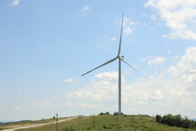 Photo of Modern wind turbine in field on sunny day. Space for text