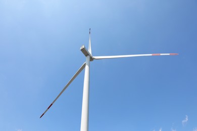 Photo of Modern wind turbine against blue sky, low angle view