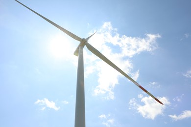 Photo of Modern wind turbine against blue sky, low angle view