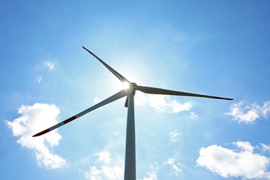 Photo of Modern wind turbine against blue sky, low angle view