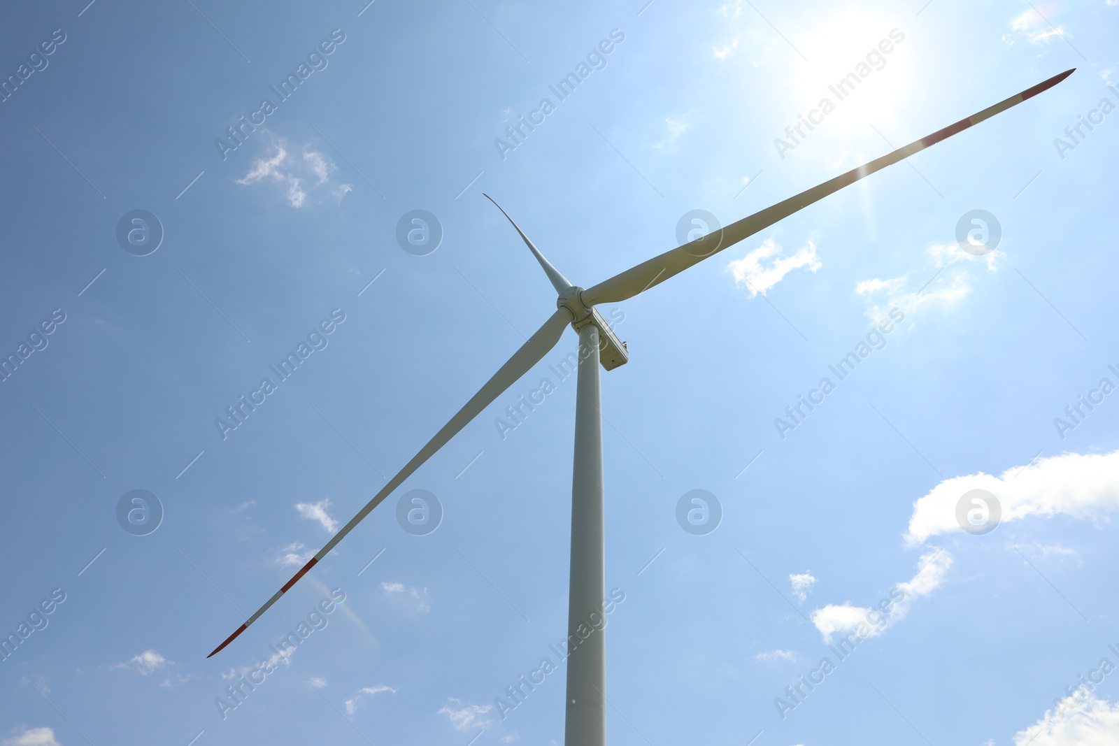Photo of Modern wind turbine against blue sky, low angle view