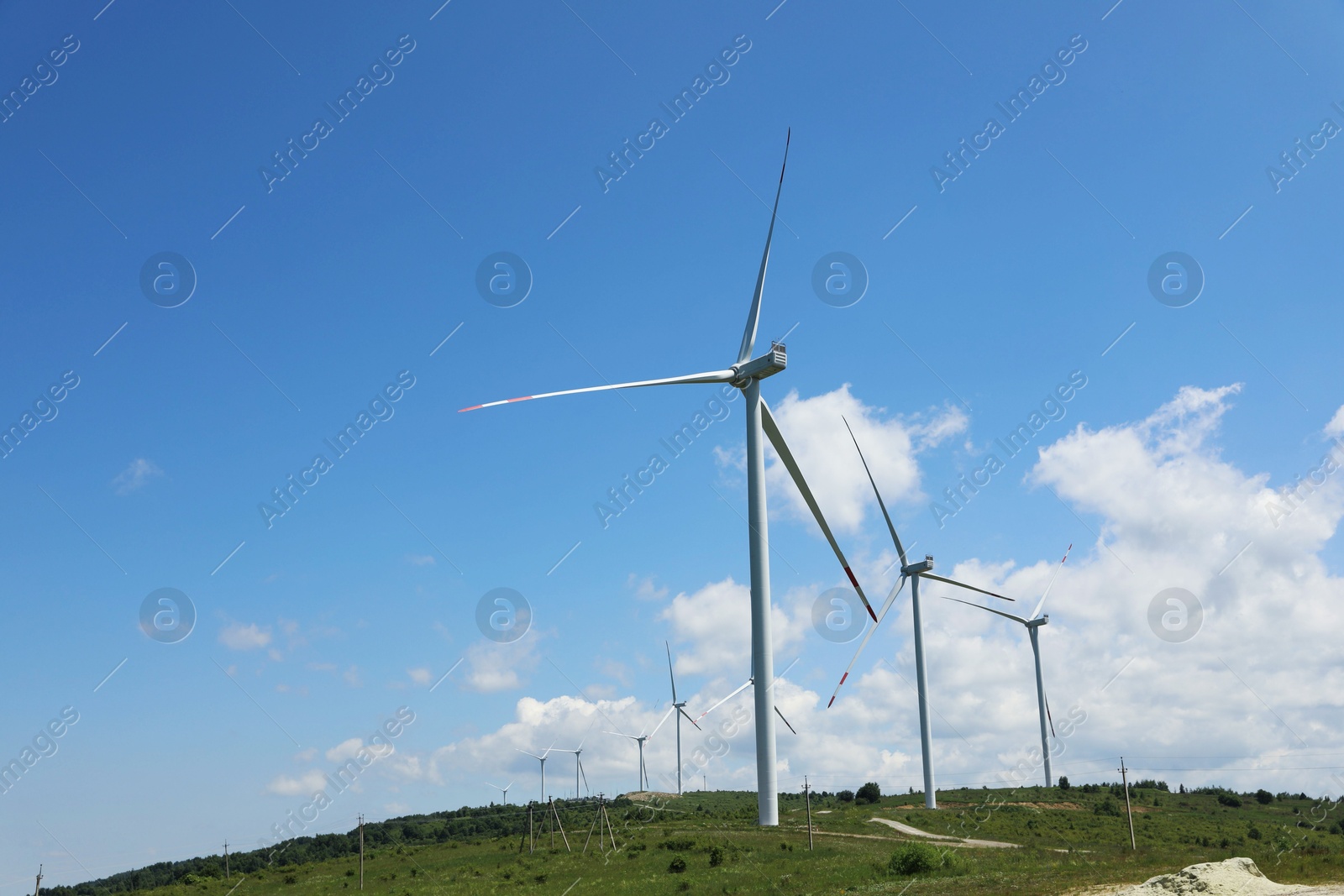 Modern wind turbines in field on sunny day. Space for text Photo of Modern wind turbines in field on sunny day. Space for text