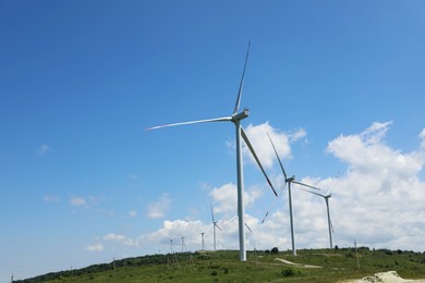 Photo of Modern wind turbines in field on sunny day. Space for text