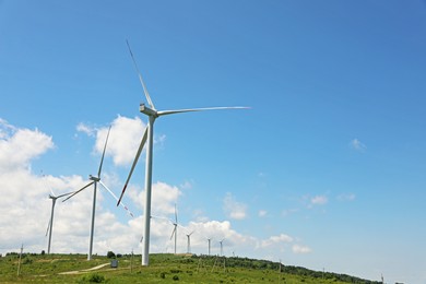 Photo of Modern wind turbines in field on sunny day. Space for text
