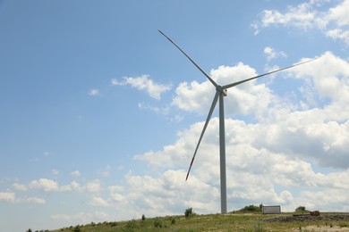 Photo of Modern wind turbine in field on sunny day. Space for text