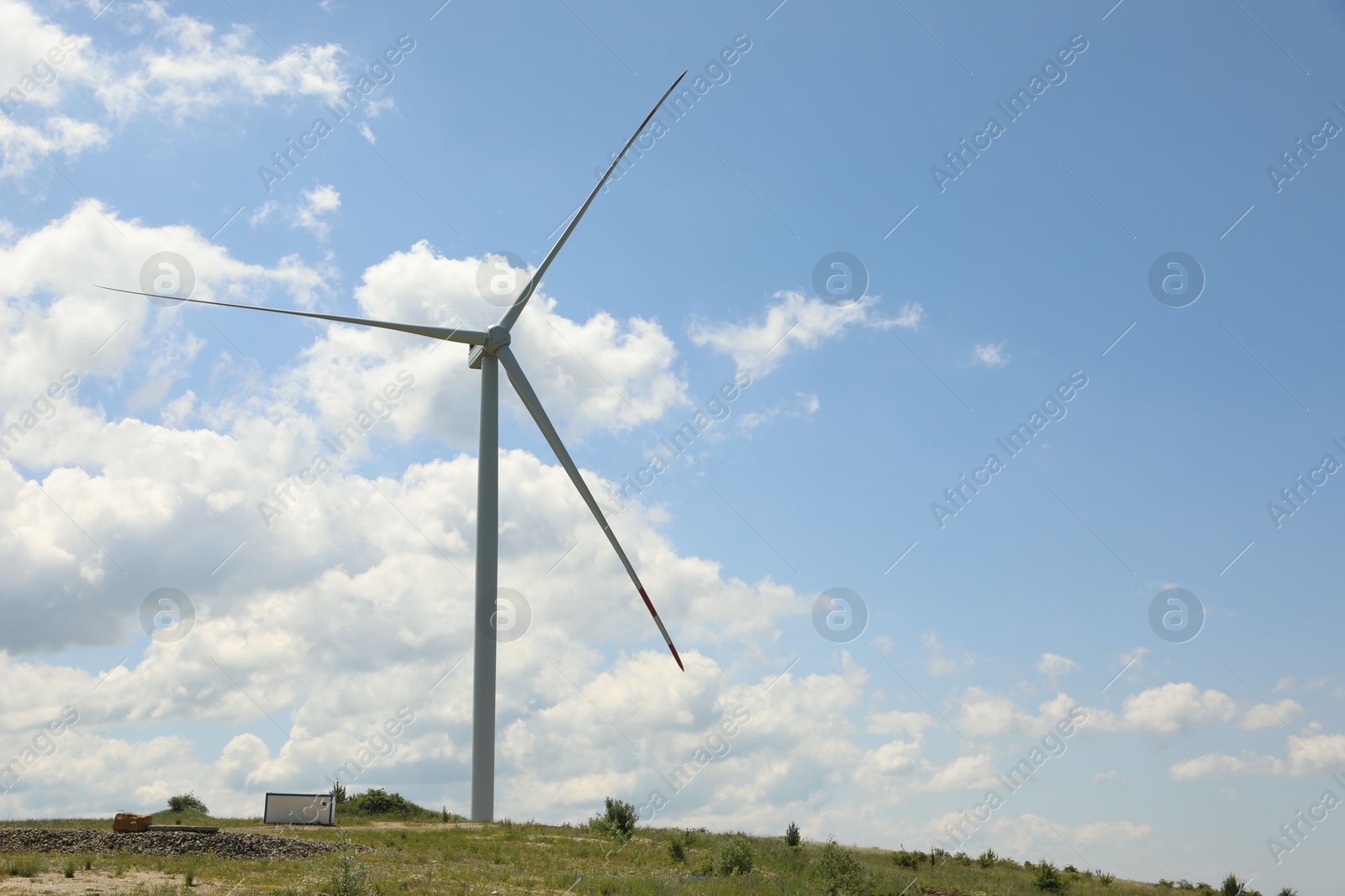 Modern wind turbine in field on sunny day. Space for text Photo of Modern wind turbine in field on sunny day. Space for text