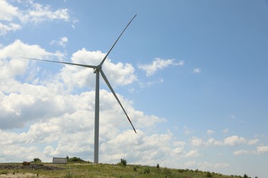 Photo of Modern wind turbine in field on sunny day. Space for text