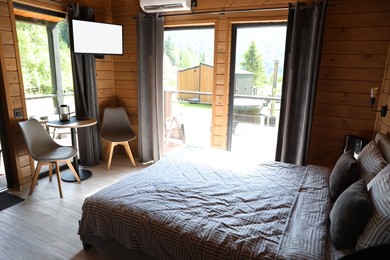Photo of Comfortable bed and table with chairs in hotel room