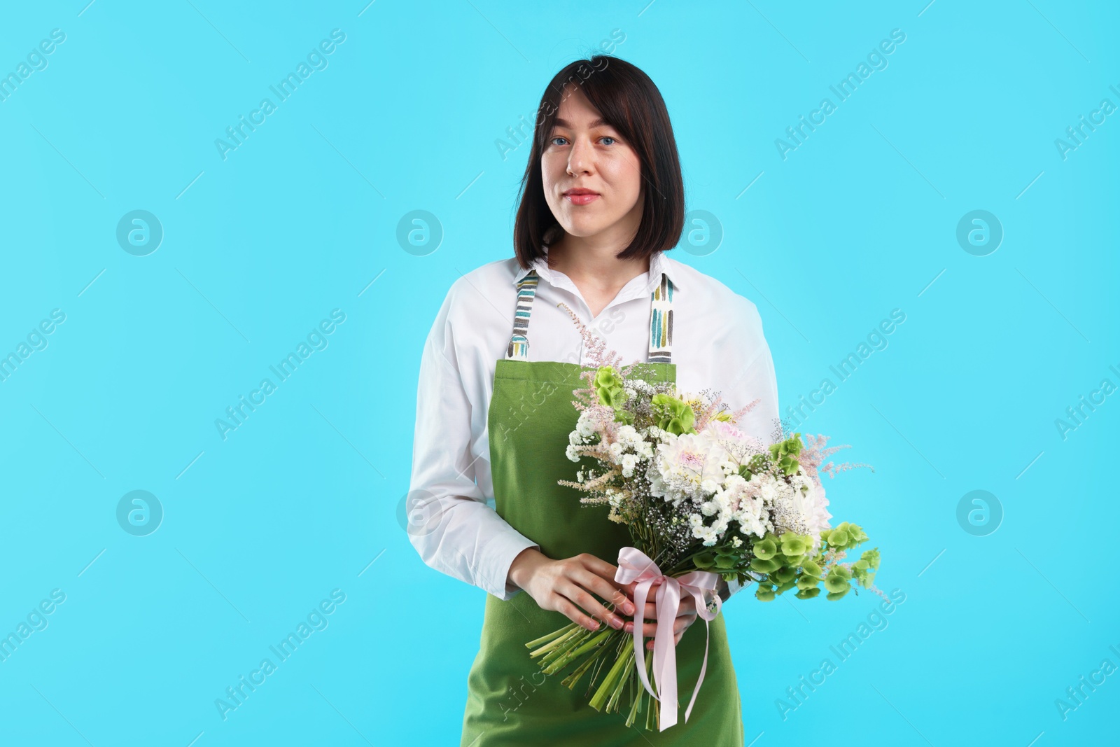 Florist with beautiful bouquet of flowers on light blue background Photo of Florist with beautiful bouquet of flowers on light blue background