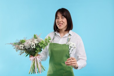 Photo of Florist with beautiful bouquet of flowers on light blue background