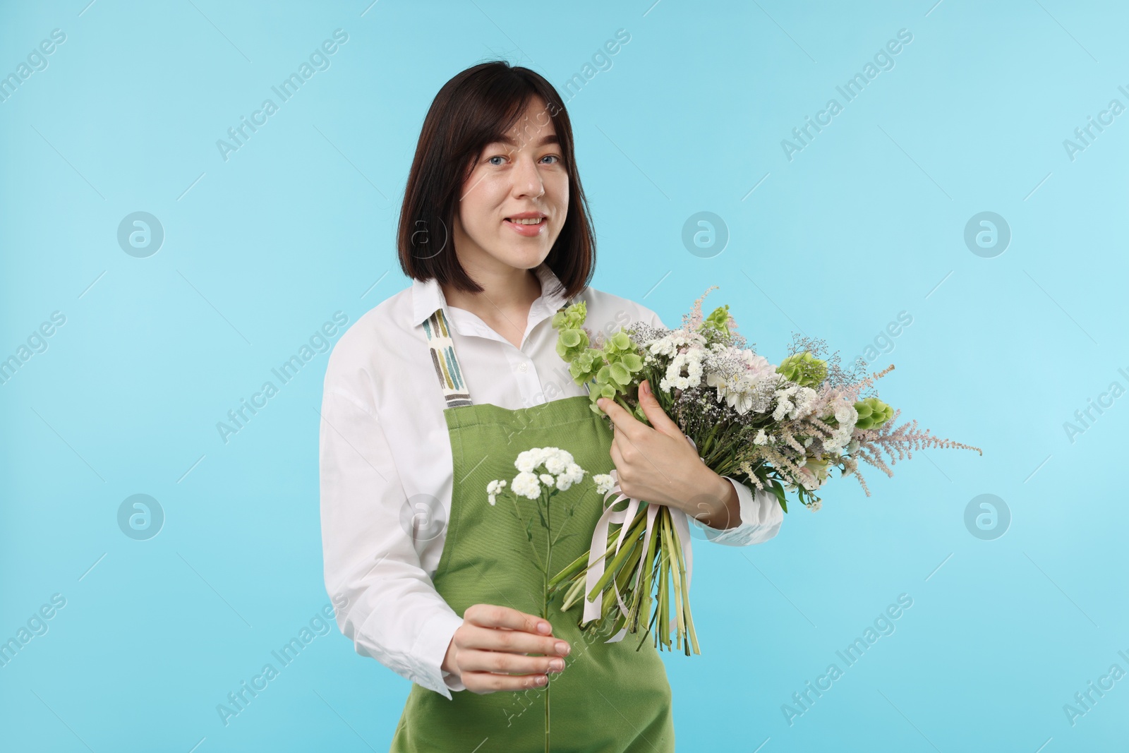 Photo of Florist with beautiful bouquet of flowers on light blue background