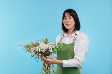 Photo of Florist with beautiful bouquet of flowers on light blue background