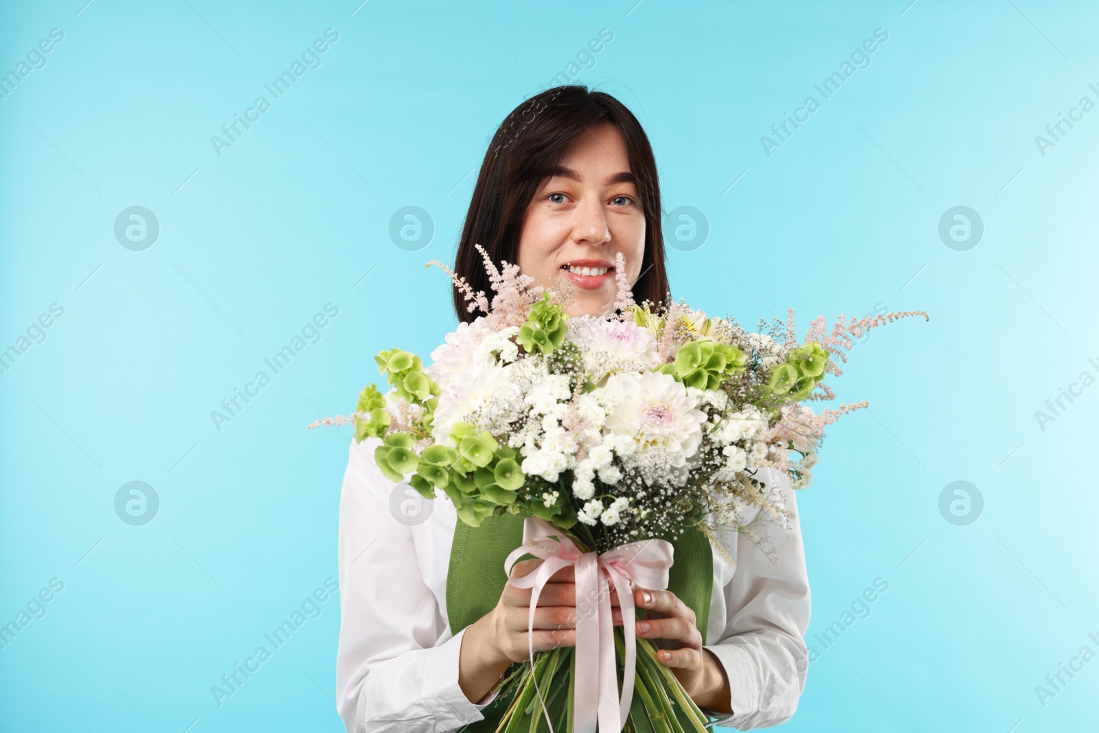 Photo of Florist with beautiful bouquet of flowers on light blue background