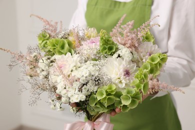 Photo of Florist with beautiful bouquet of flowers indoors, closeup