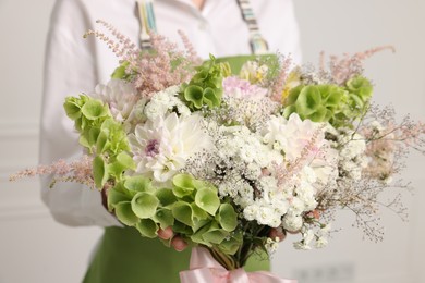 Photo of Florist with beautiful bouquet of flowers indoors, closeup