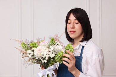 Photo of Florist with beautiful bouquet of flowers near white wall indoors