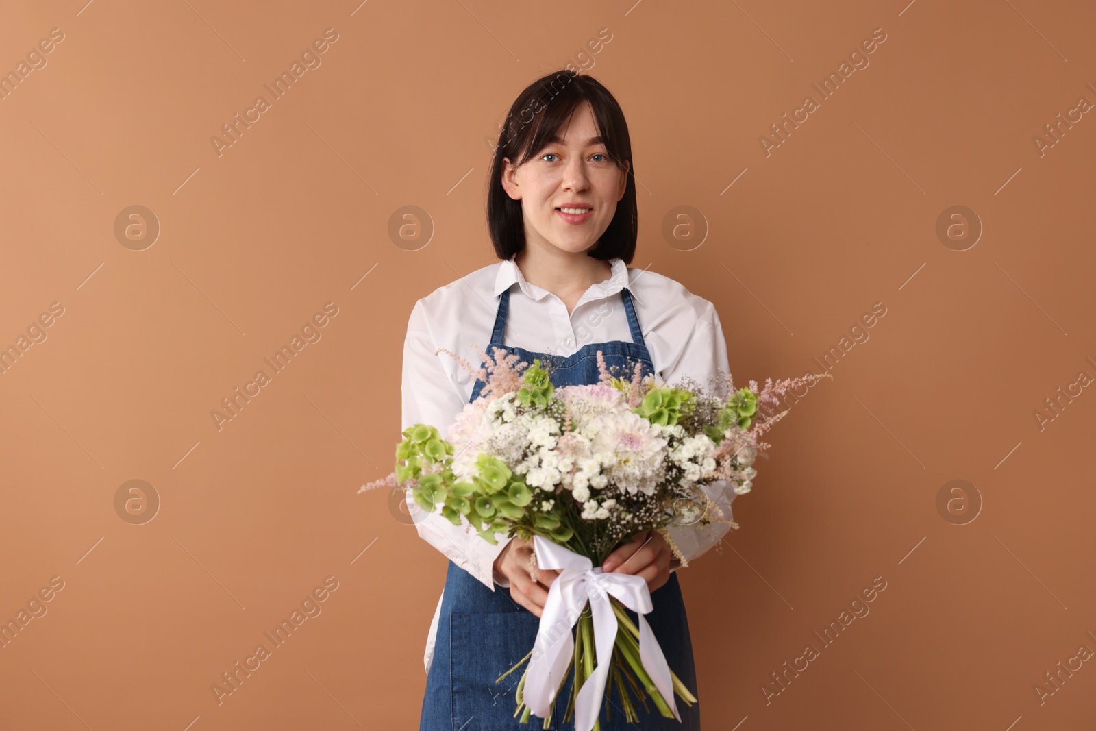 Photo of Florist with beautiful bouquet of flowers on dark beige background