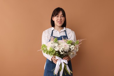 Photo of Florist with beautiful bouquet of flowers on dark beige background