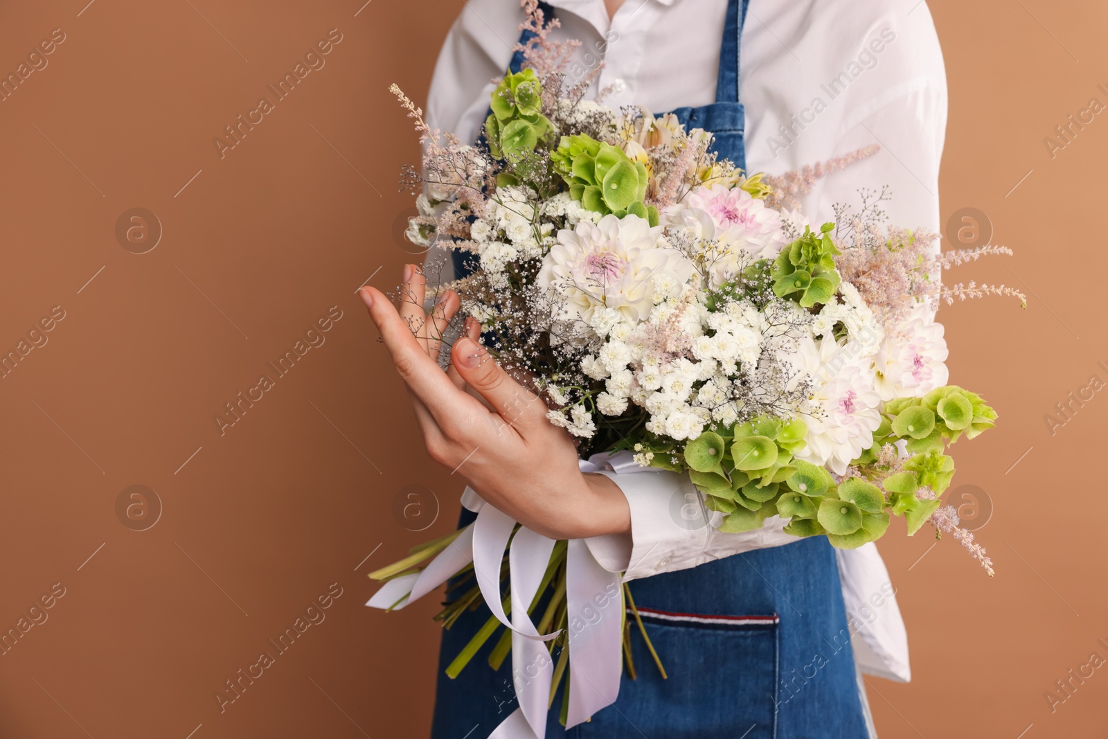 Florist with beautiful bouquet of flowers on dark beige background, closeup. Space for text Photo of Florist with beautiful bouquet of flowers on dark beige background, closeup. Space for text