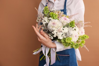 Photo of Florist with beautiful bouquet of flowers on dark beige background, closeup. Space for text