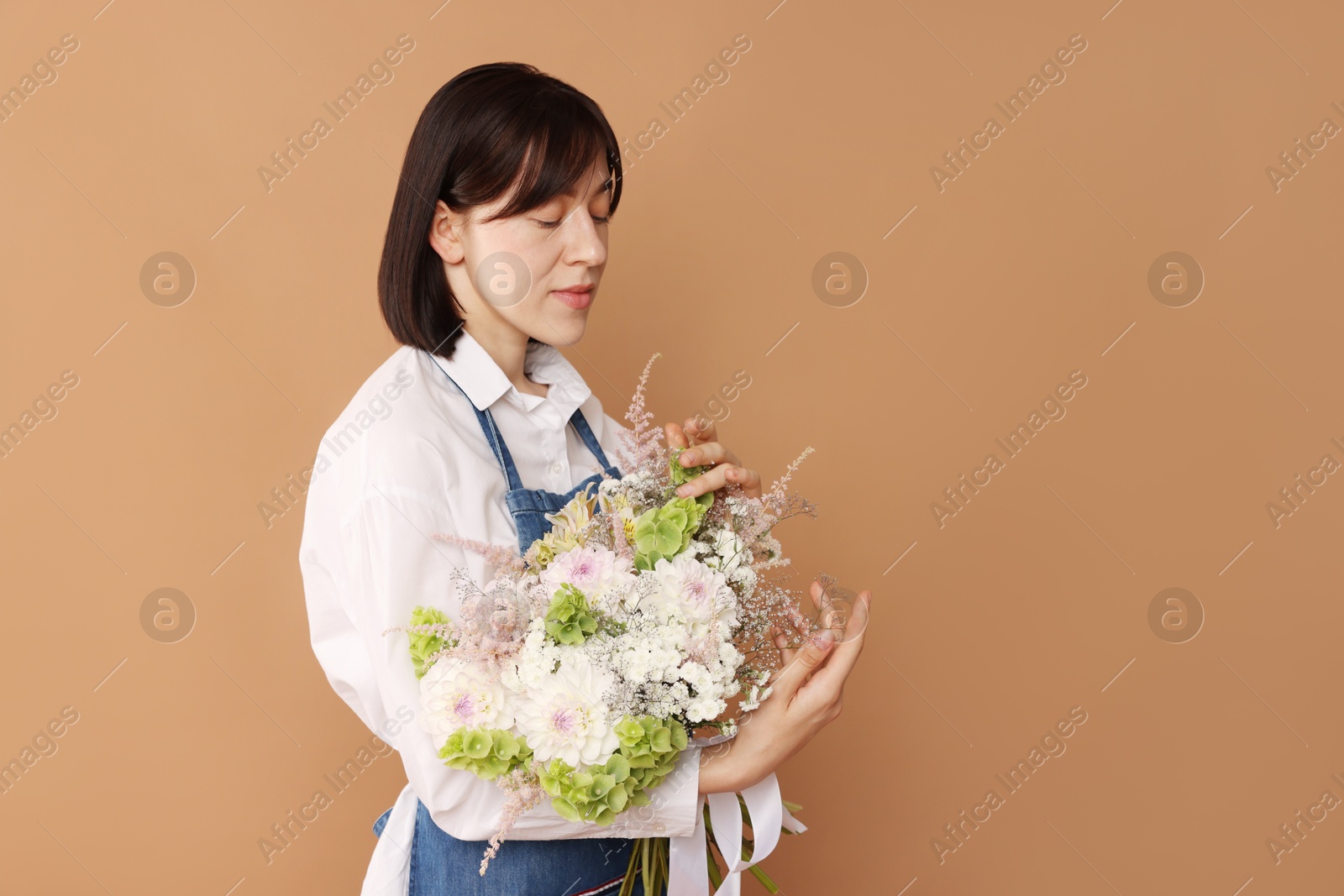 Florist with beautiful bouquet of flowers on beige background, space for text Photo of Florist with beautiful bouquet of flowers on beige background, space for text