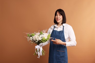 Photo of Florist with beautiful bouquet of flowers on dark beige background