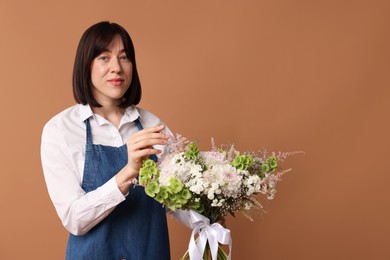 Photo of Florist with beautiful bouquet of flowers on dark beige background