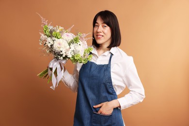 Photo of Florist with beautiful bouquet of flowers on dark beige background