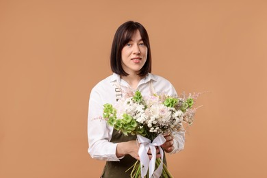 Photo of Florist with beautiful bouquet of flowers on beige background