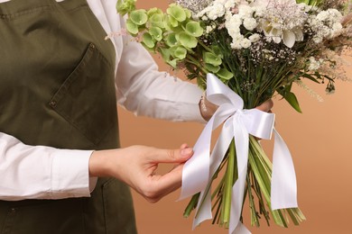 Photo of Florist with beautiful bouquet of flowers on beige background, closeup