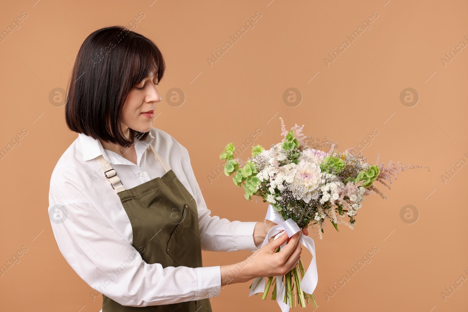 Photo of Florist with beautiful bouquet of flowers on beige background