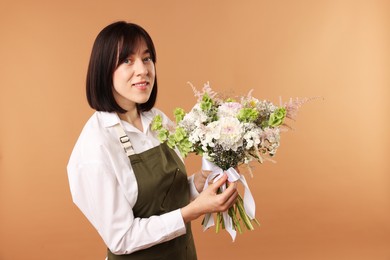 Photo of Florist with beautiful bouquet of flowers on beige background