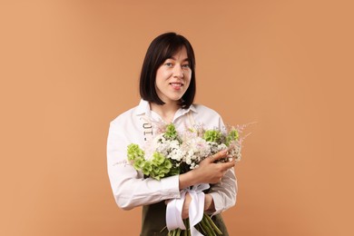 Photo of Florist with beautiful bouquet of flowers on beige background