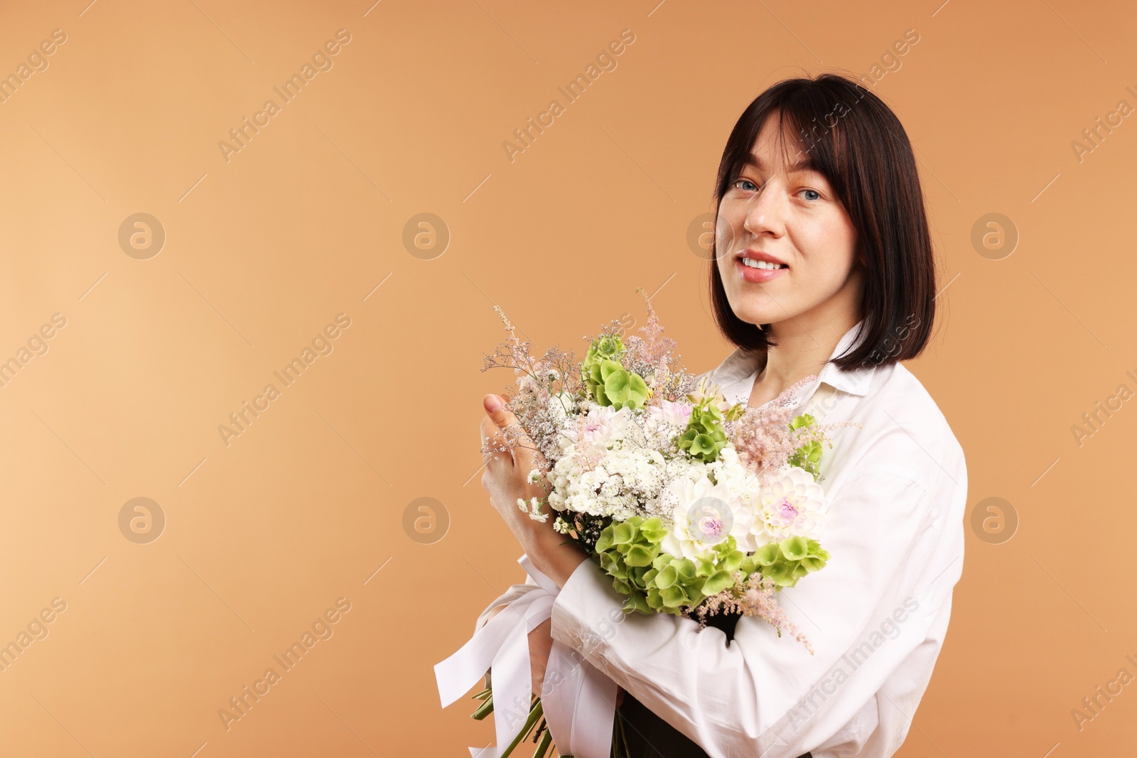 Florist with beautiful bouquet of flowers on beige background, space for text Photo of Florist with beautiful bouquet of flowers on beige background, space for text