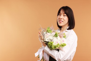 Photo of Florist with beautiful bouquet of flowers on beige background, space for text