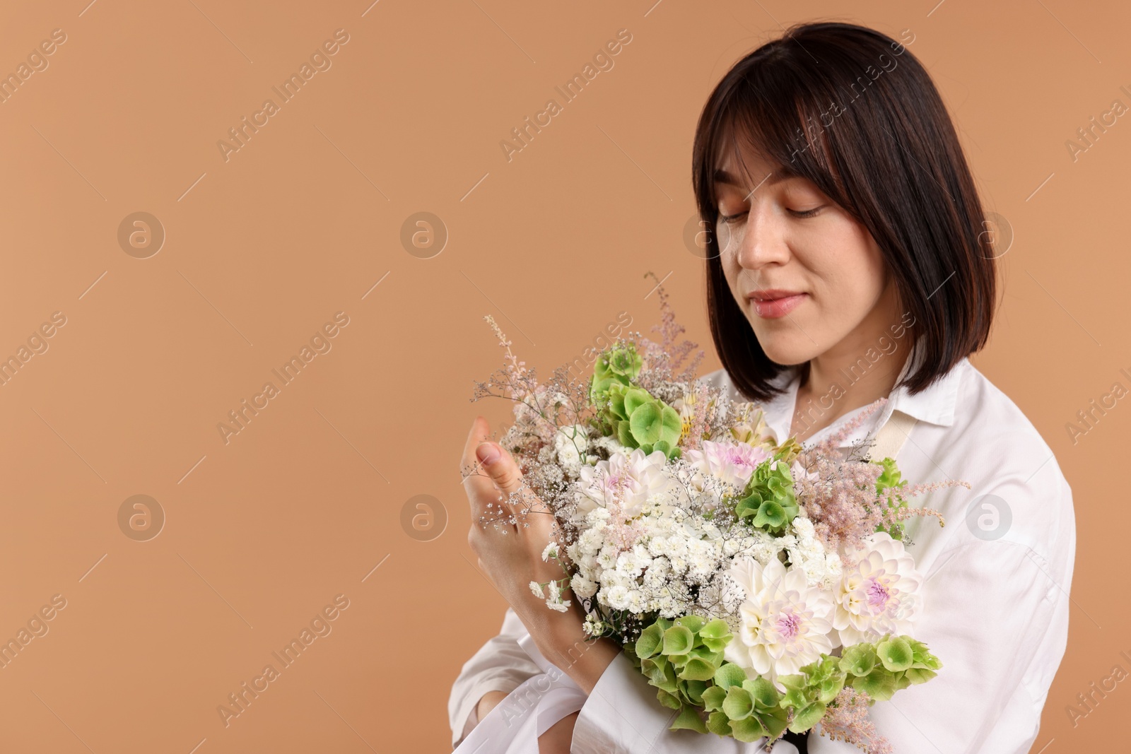 Florist with beautiful bouquet of flowers on beige background, space for text Photo of Florist with beautiful bouquet of flowers on beige background, space for text