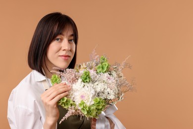 Photo of Florist with beautiful bouquet of flowers on beige background, space for text