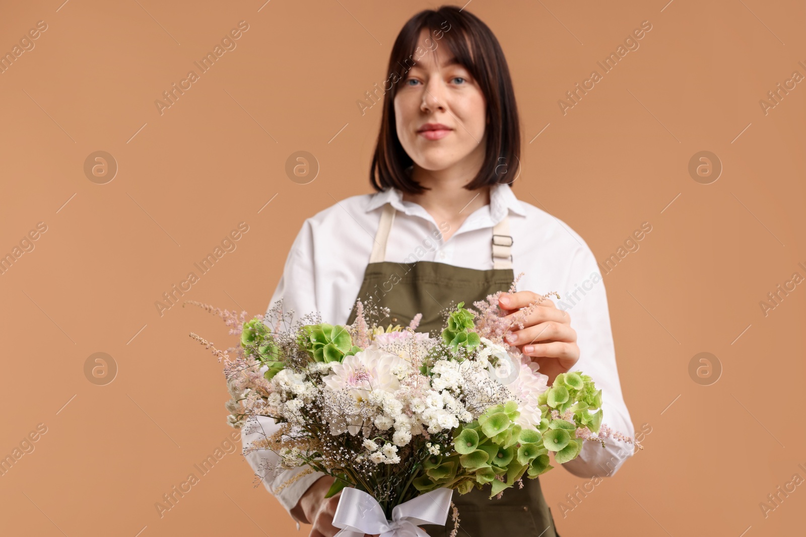 Florist with beautiful bouquet of flowers on beige background Photo of Florist with beautiful bouquet of flowers on beige background