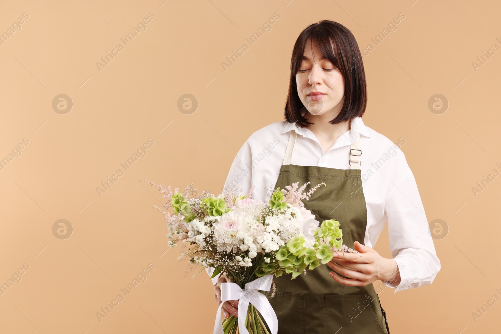 Florist with beautiful bouquet of flowers on beige background, space for text Photo of Florist with beautiful bouquet of flowers on beige background, space for text