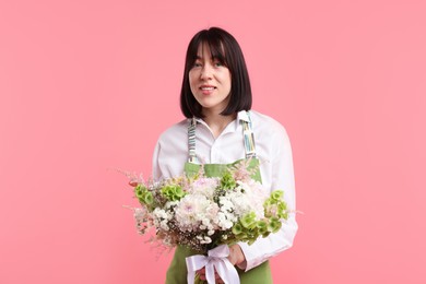 Photo of Florist with beautiful bouquet of flowers on pink background