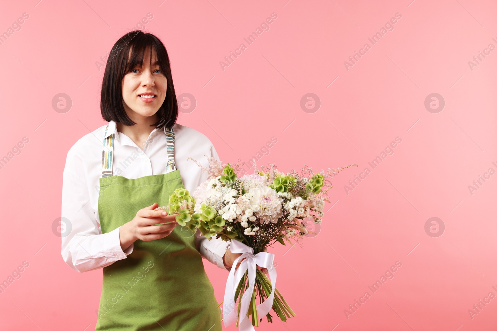 Florist with beautiful bouquet of flowers on pink background, space for text Photo of Florist with beautiful bouquet of flowers on pink background, space for text