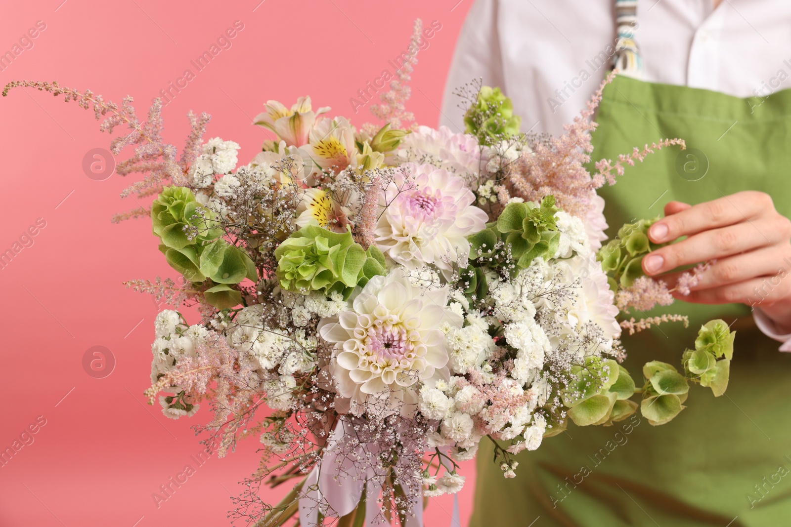 Photo of Florist with beautiful bouquet of flowers on pink background, closeup