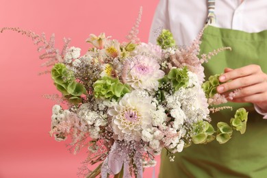 Photo of Florist with beautiful bouquet of flowers on pink background, closeup