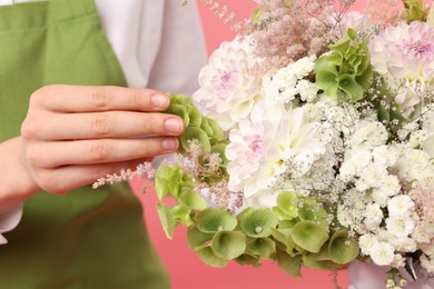 Photo of Florist with beautiful bouquet of flowers on pink background, closeup