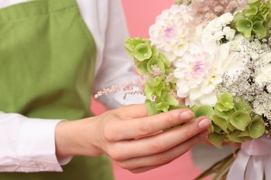 Photo of Florist with beautiful bouquet of flowers on pink background, closeup