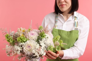 Photo of Florist with beautiful bouquet of flowers on pink background, closeup
