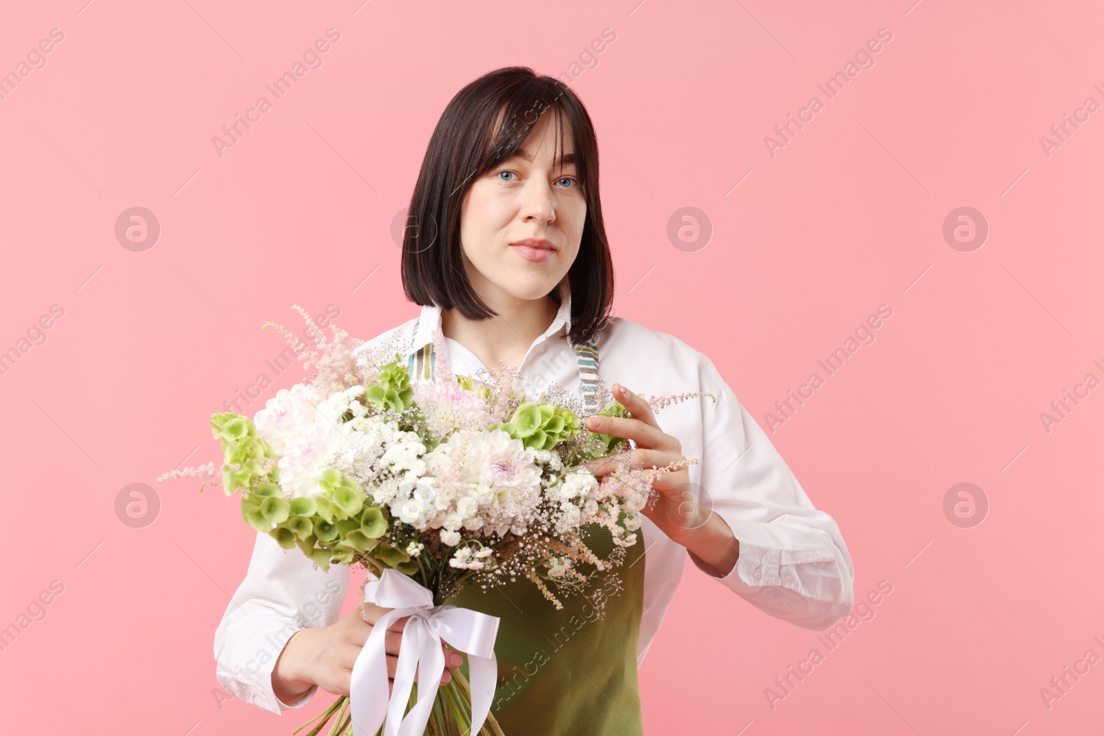 Florist with beautiful bouquet of flowers on pink background Photo of Florist with beautiful bouquet of flowers on pink background