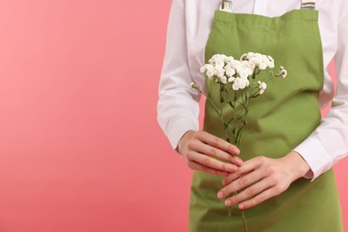 Photo of Florist with beautiful flowers on pink background, closeup. Space for text