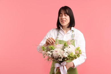 Photo of Florist with beautiful bouquet of flowers on pink background, space for text