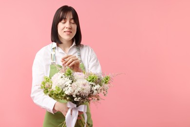 Photo of Florist with beautiful bouquet of flowers on pink background, space for text